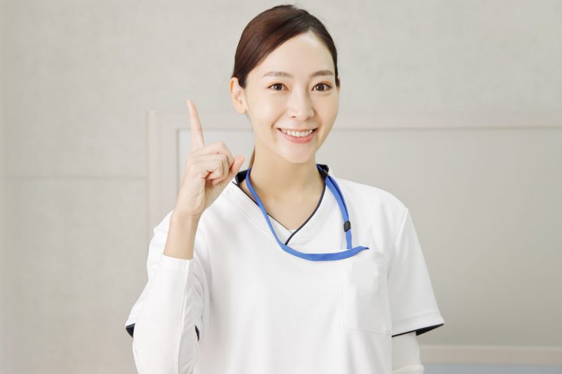 指差しポーズの笑顔の看護師の女性