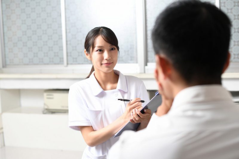 医療従事者（看護師）の女性と問診を受ける男性患者