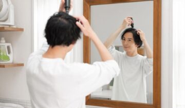 鏡を見ながら育毛剤をつける男性
