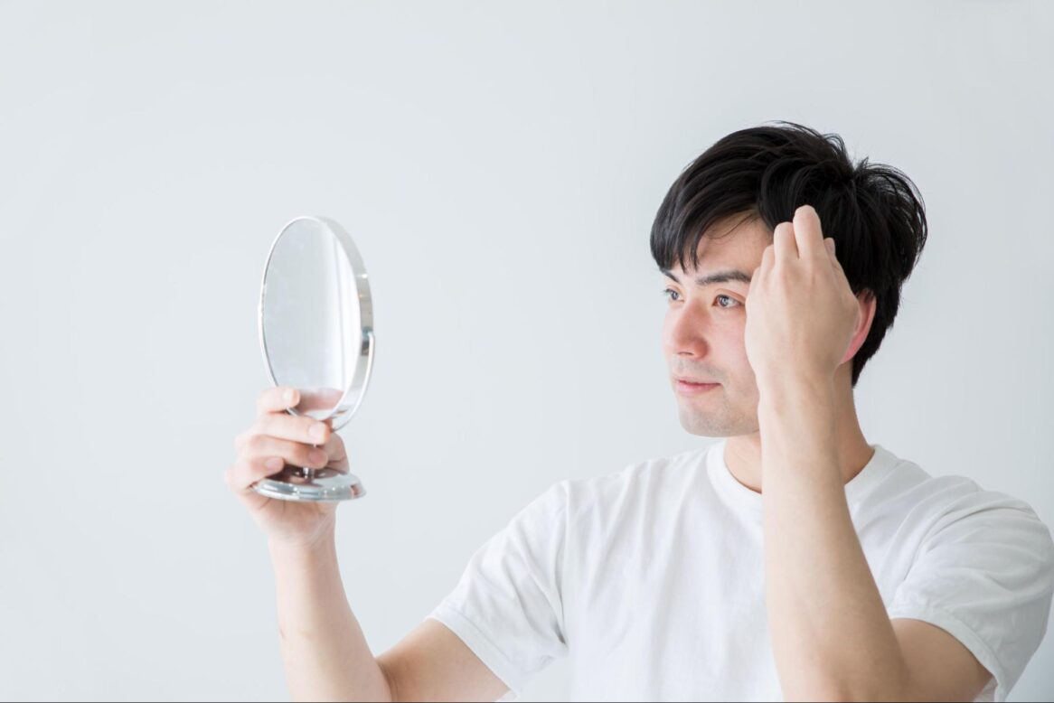 鏡を見ながら髪の毛を触る男性