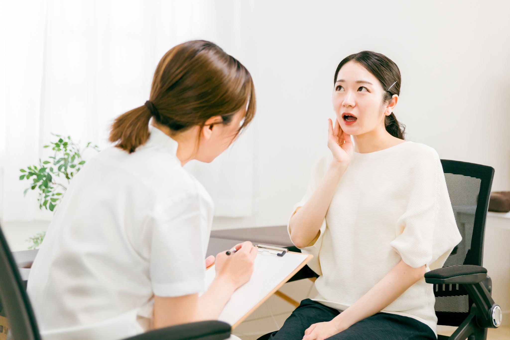 エラ部分を押さえながらボトックス注射について医師に相談している女性