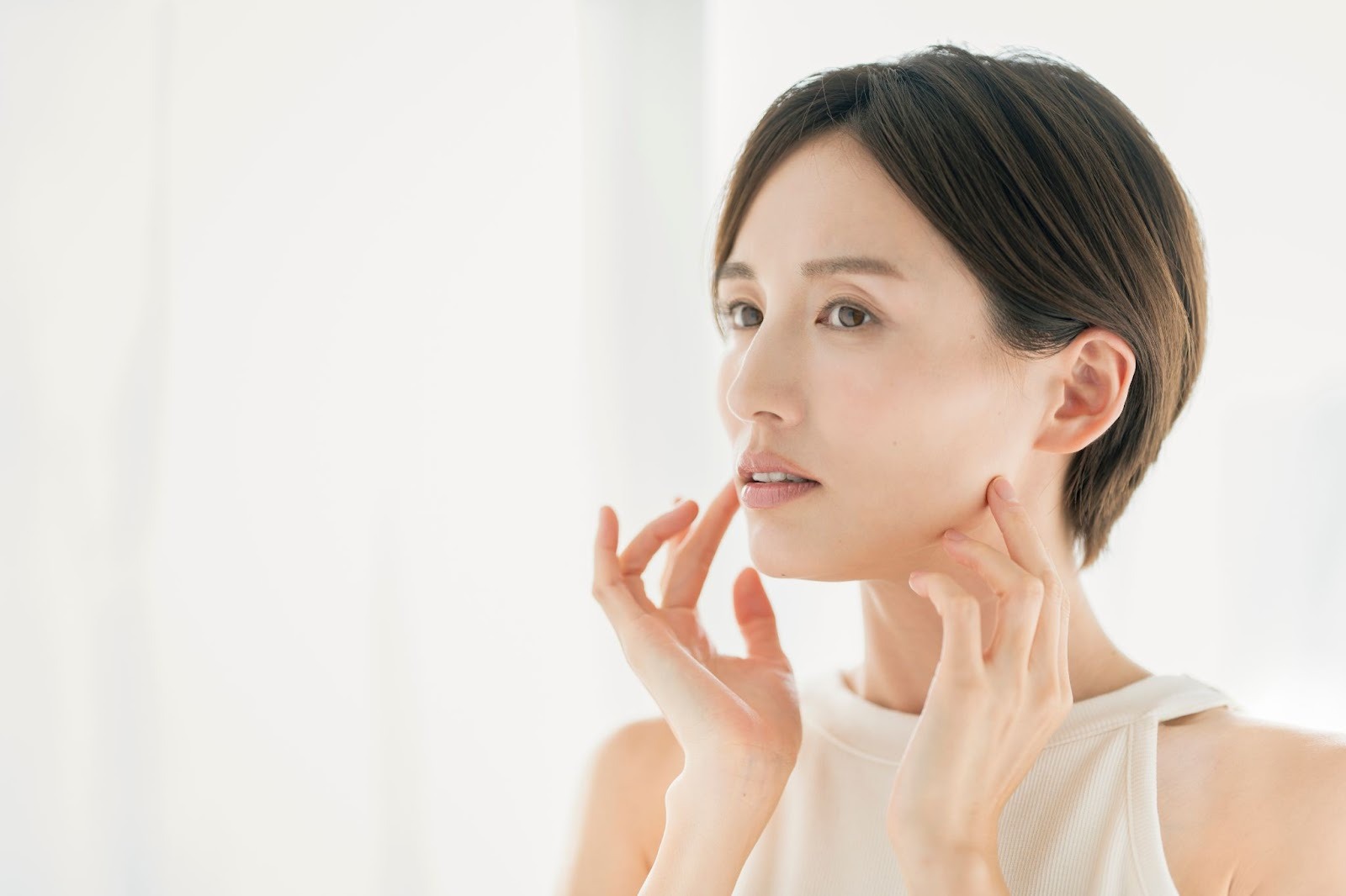 たるみを気にして肌に触れている女性