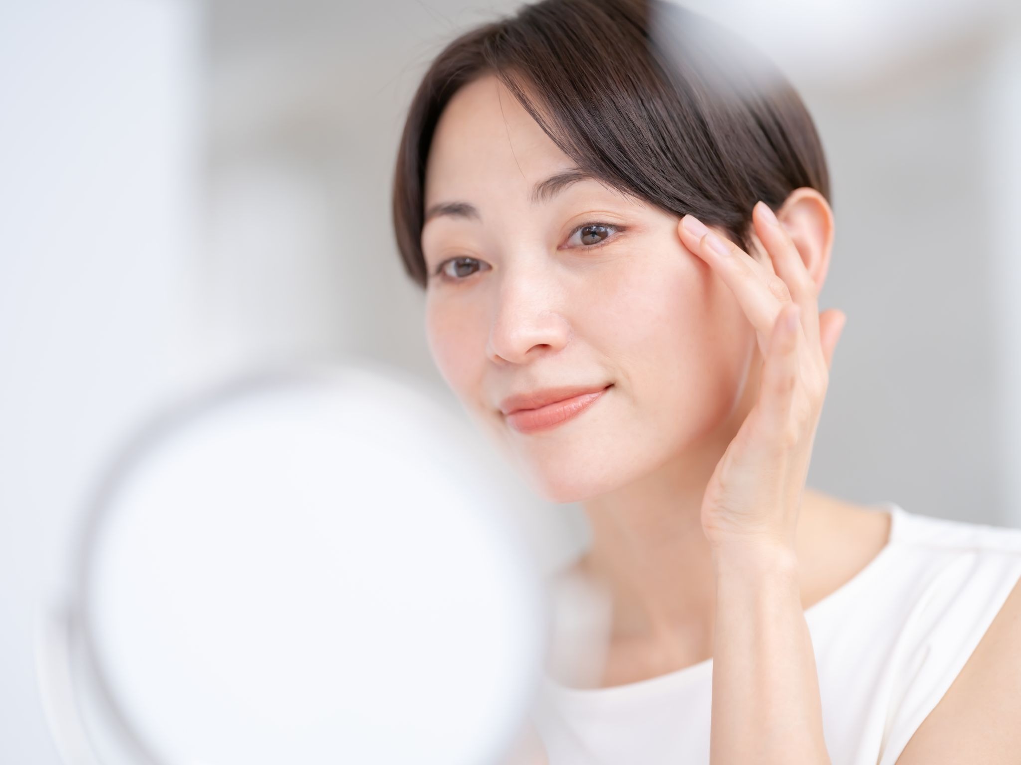 鏡を見てしわを気にしている女性