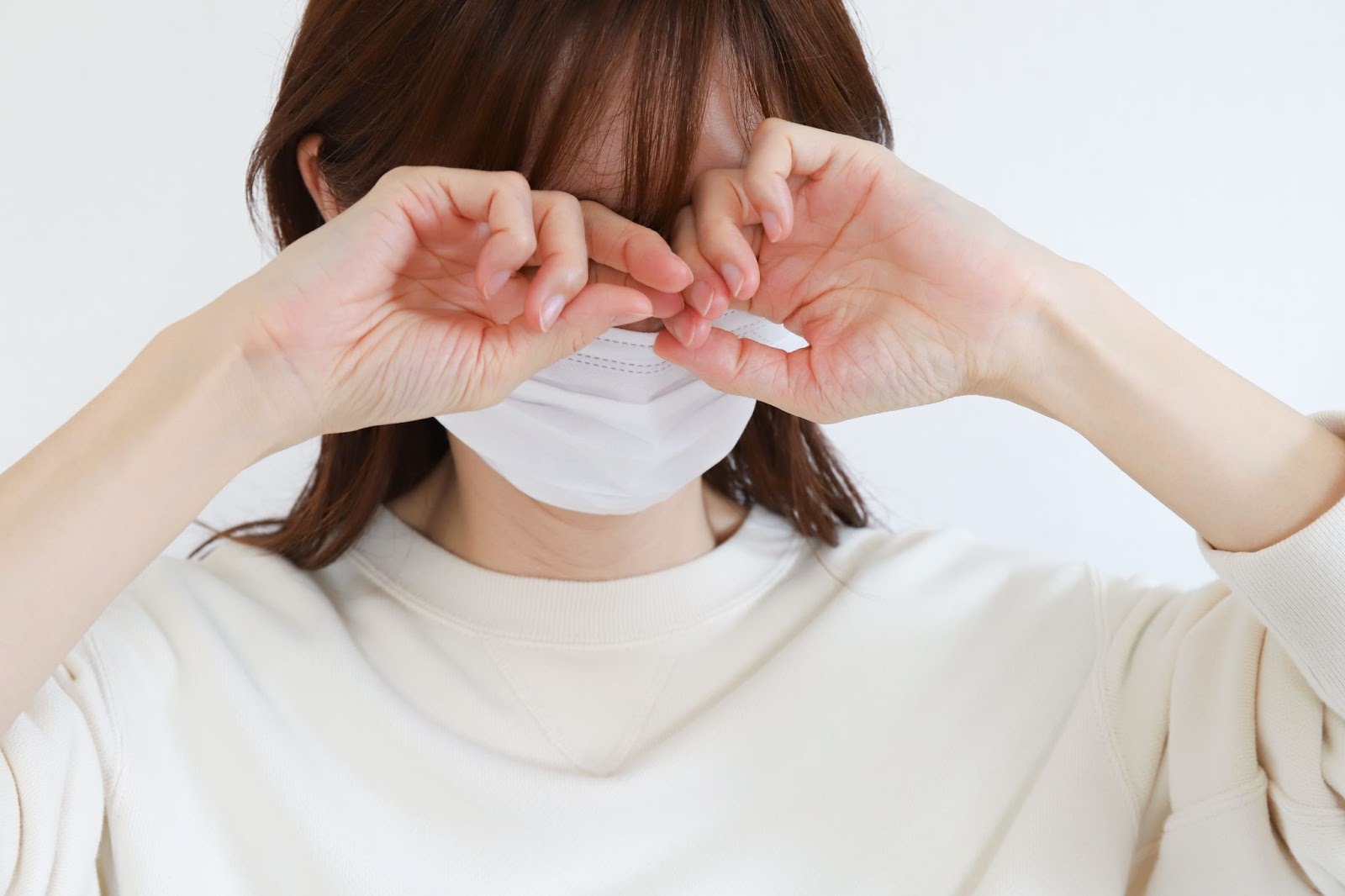 目をこすっているマスクの女性