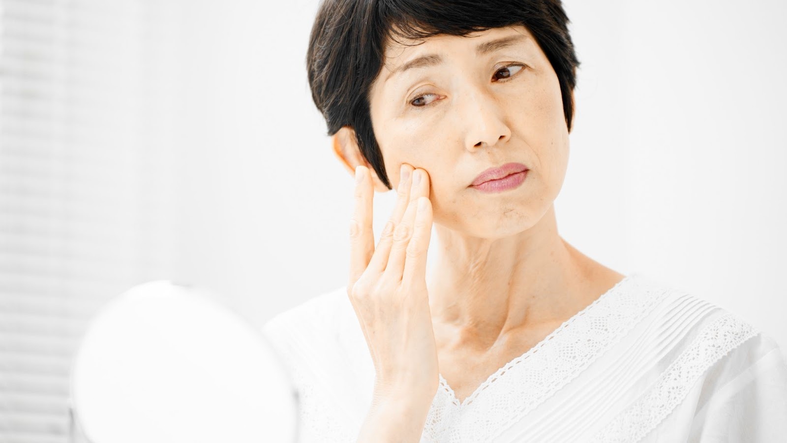 鏡を見てほうれい線を気にする女性