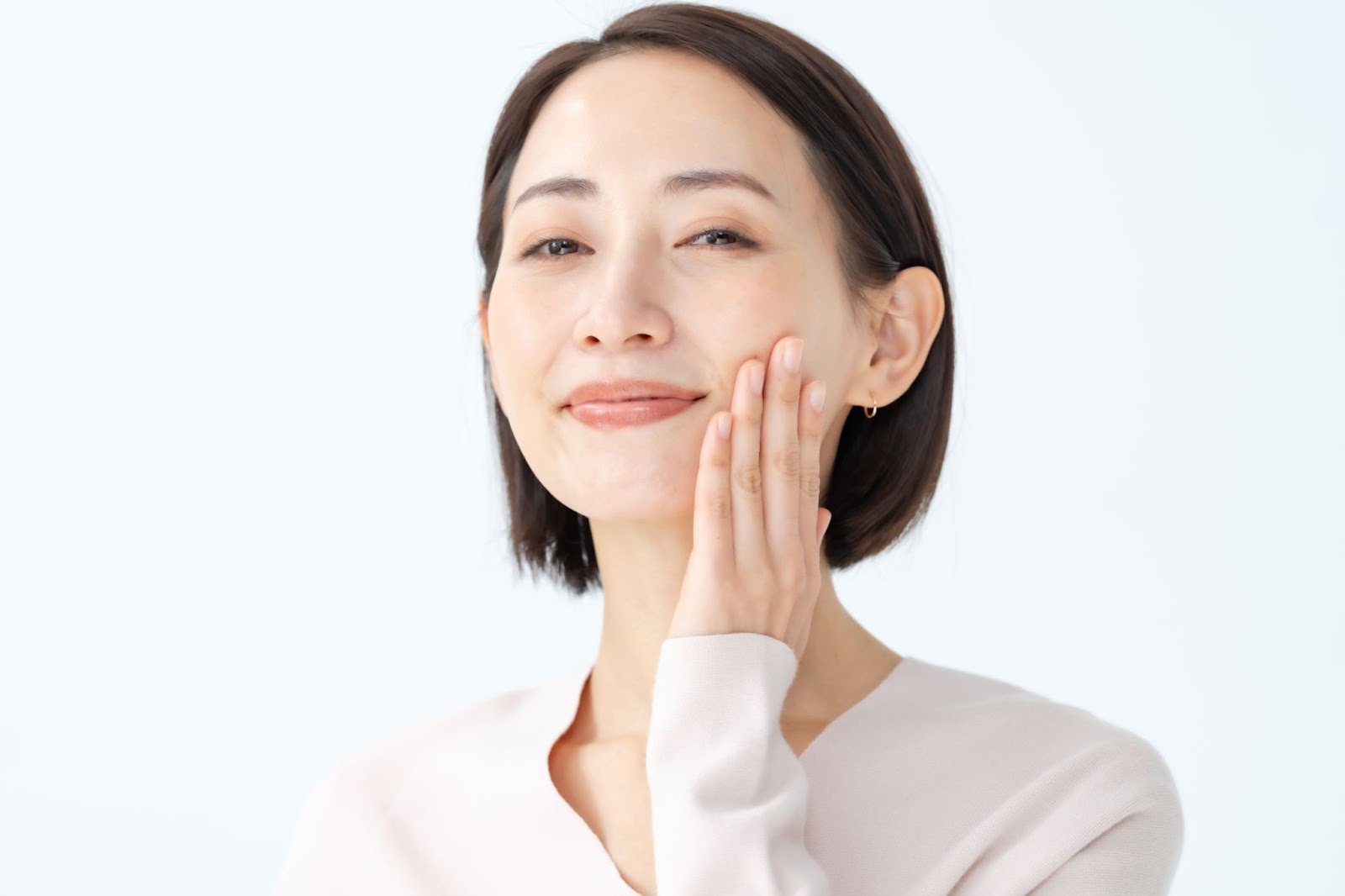 笑顔で頬に触れている女性