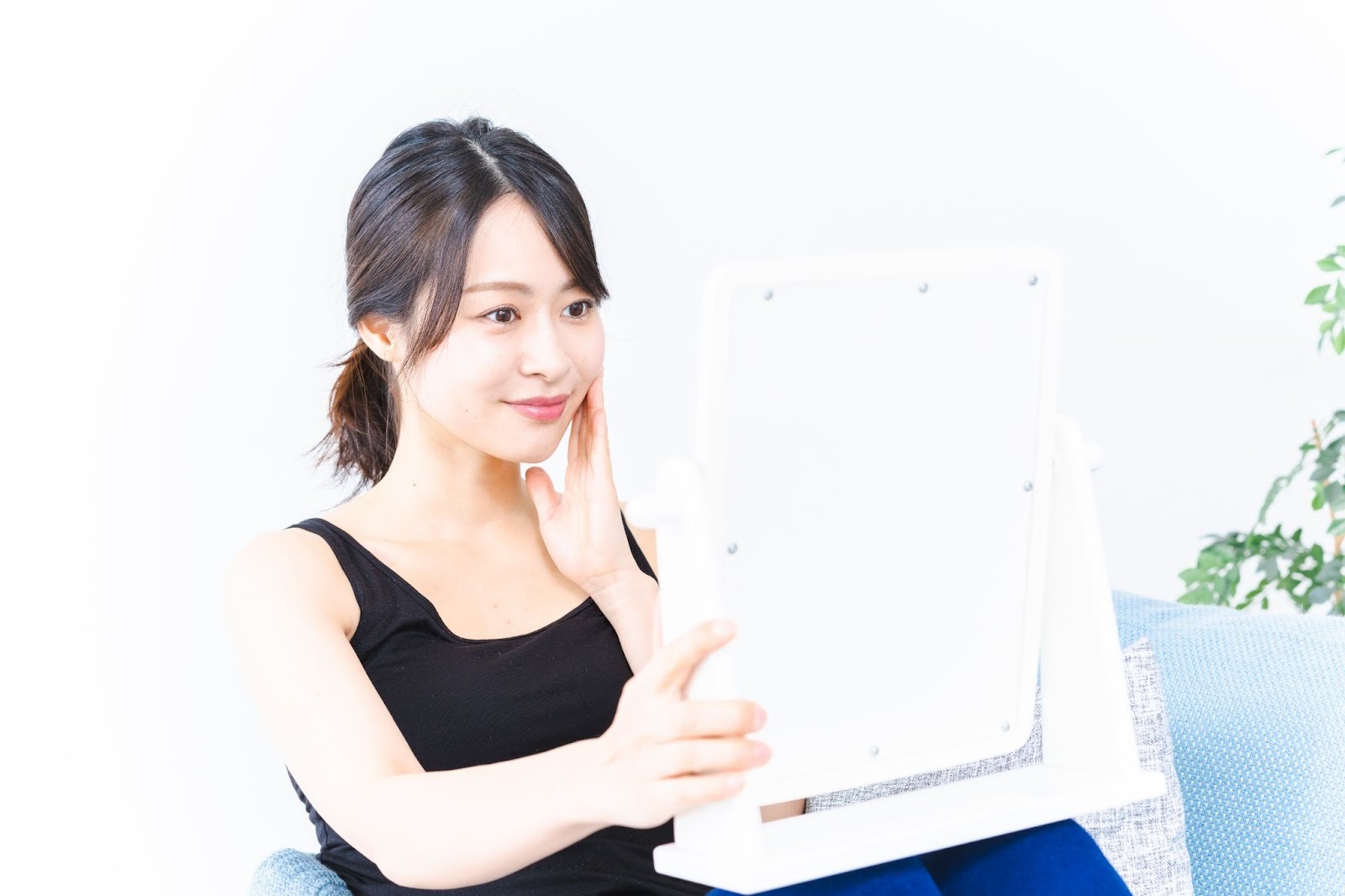 鏡を見ておでこのしわをチェックしている女性