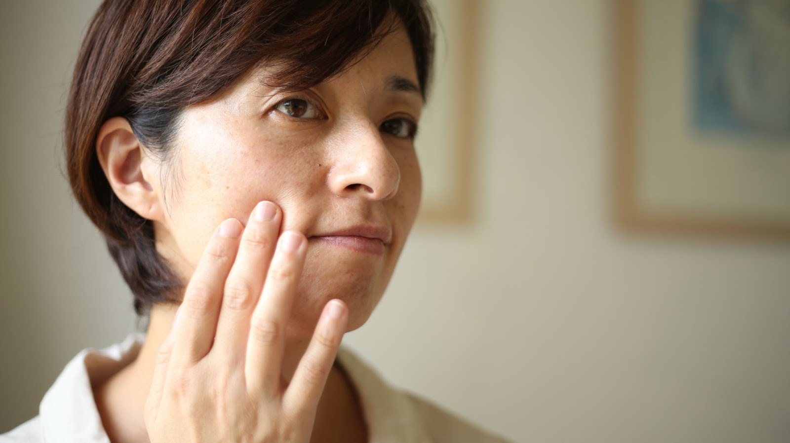 顔のたるみを気にして頬に手を当てている女性
