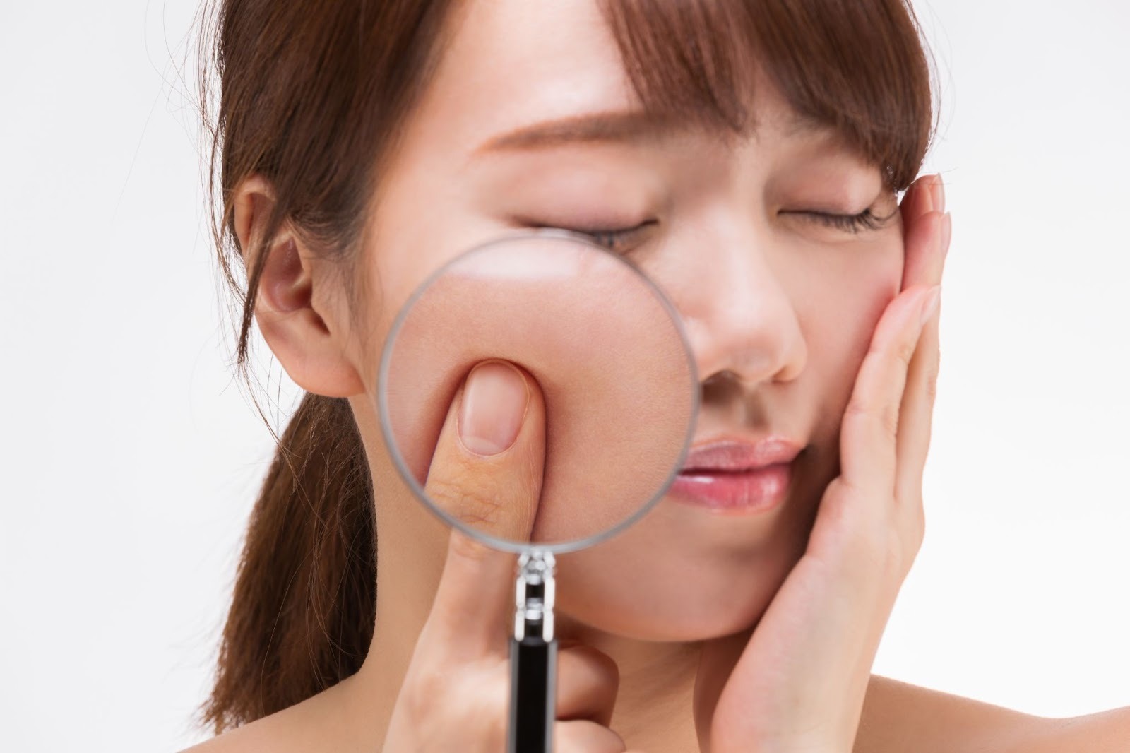 女性の肌を虫眼鏡で覗いてシミやそばかす、肝斑をチェックしている様子