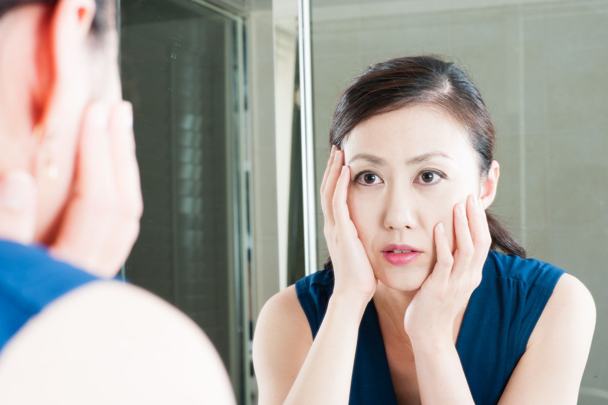 ほうれい線を気にして鏡を見ている女性