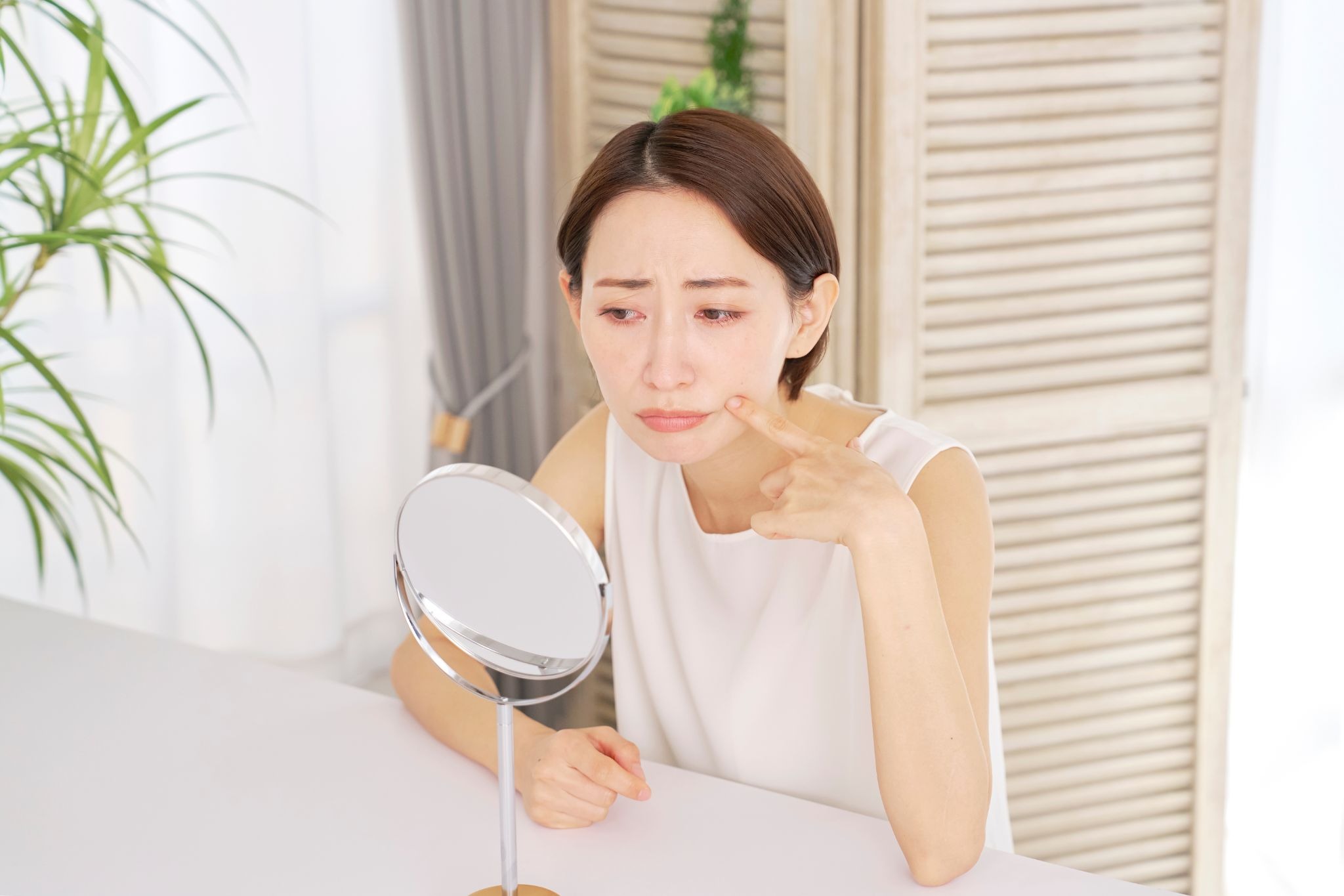 顎のたるみを気にして鏡を見ている女性
