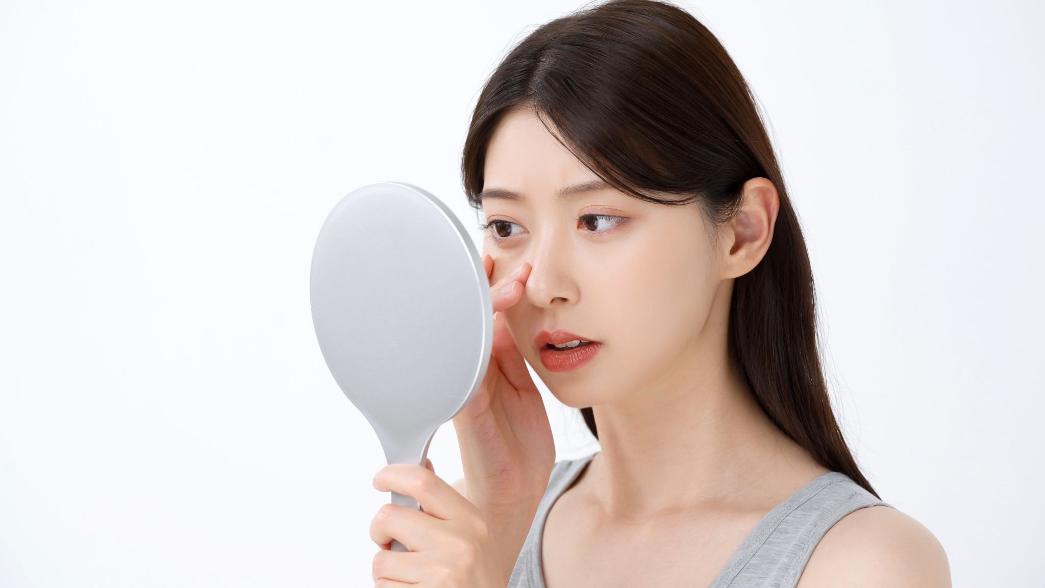 鼻を鏡で見ている女性