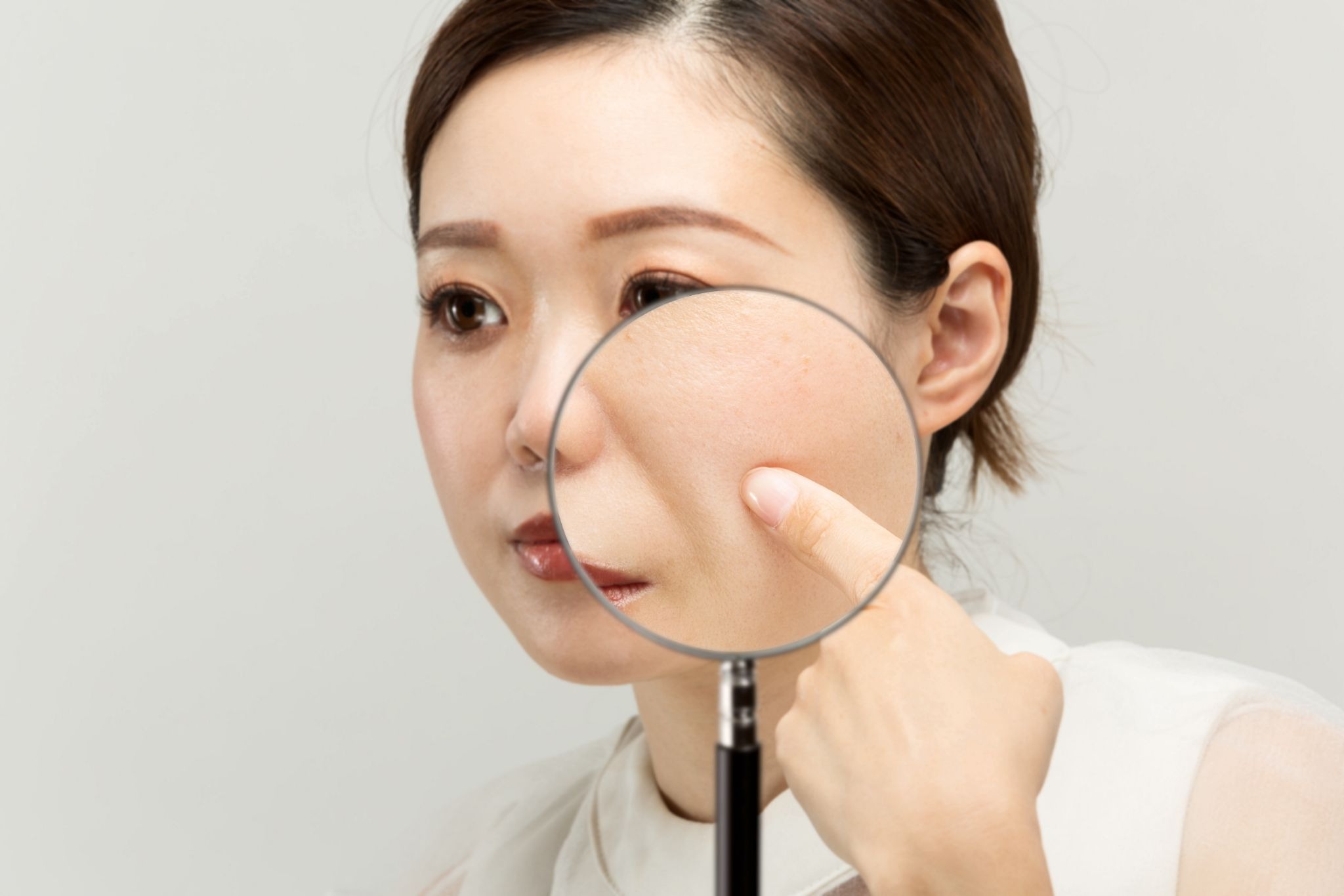 ほうれい線を指さす女性