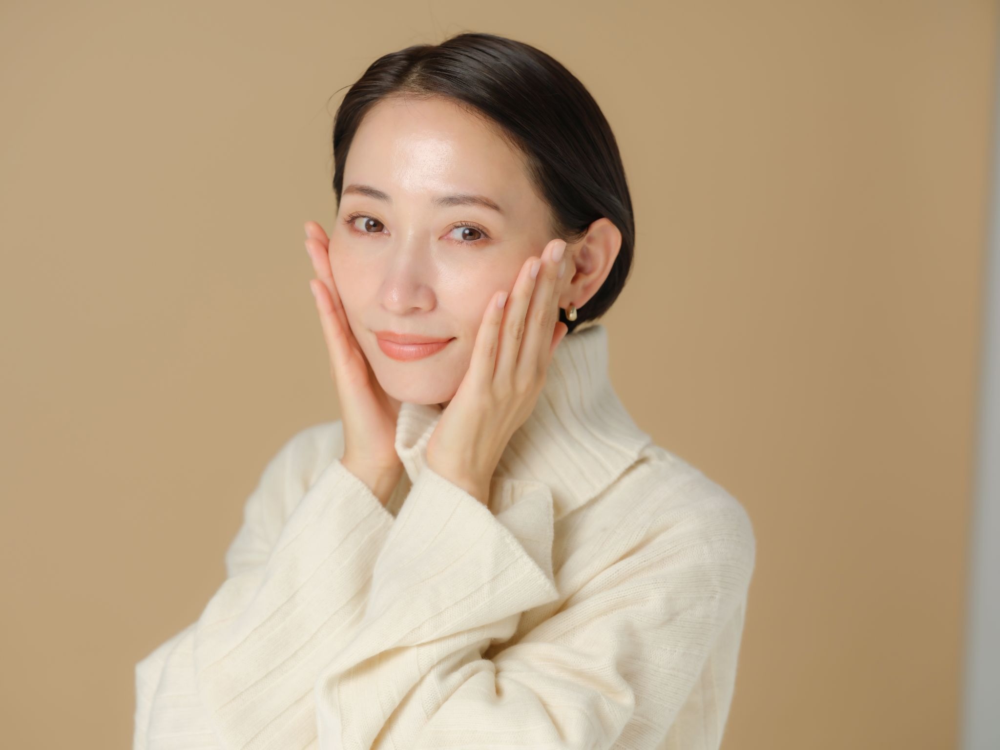 頬を両手で押さえている女性