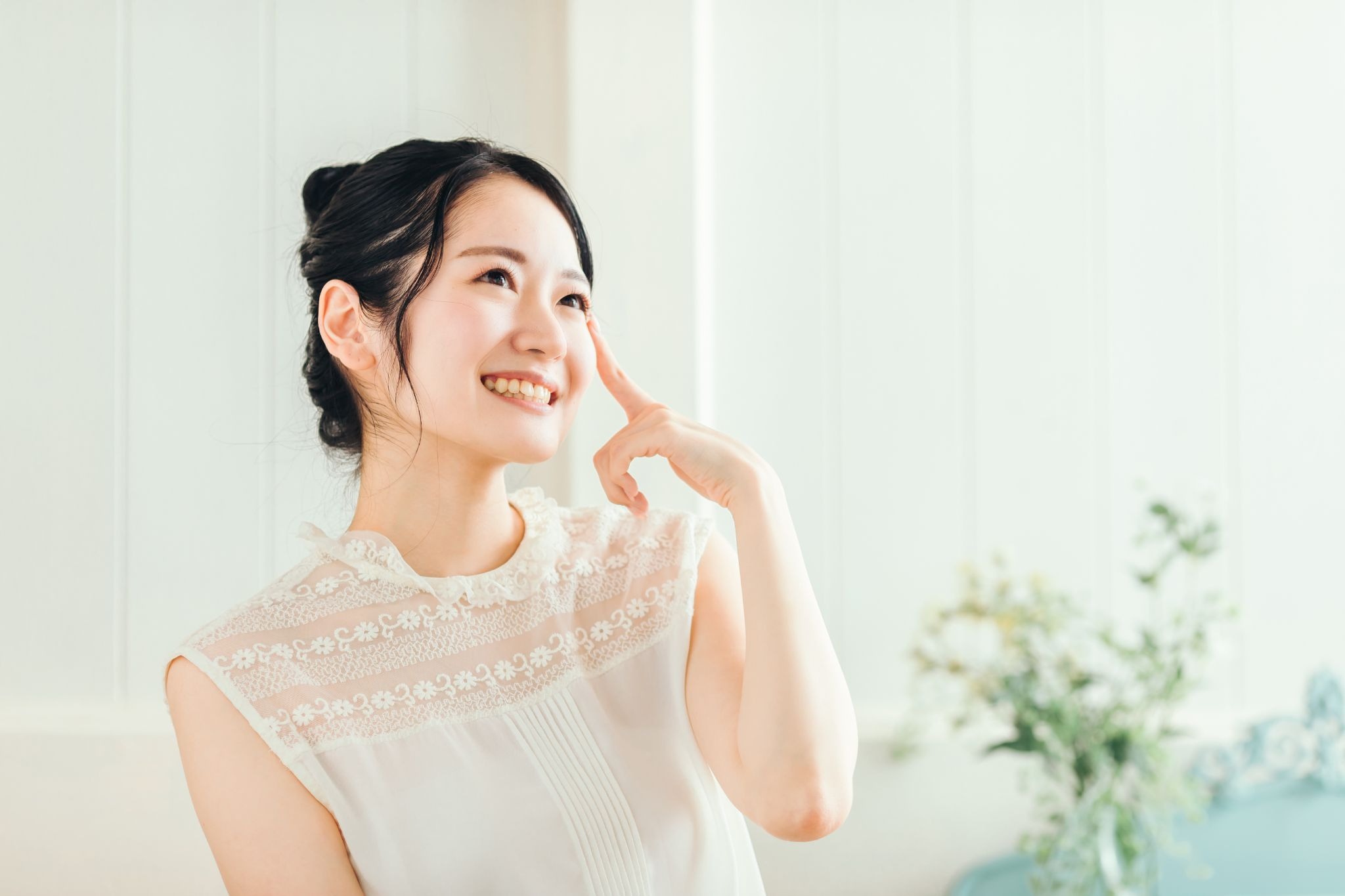 涙袋に手を当てて笑顔の女性