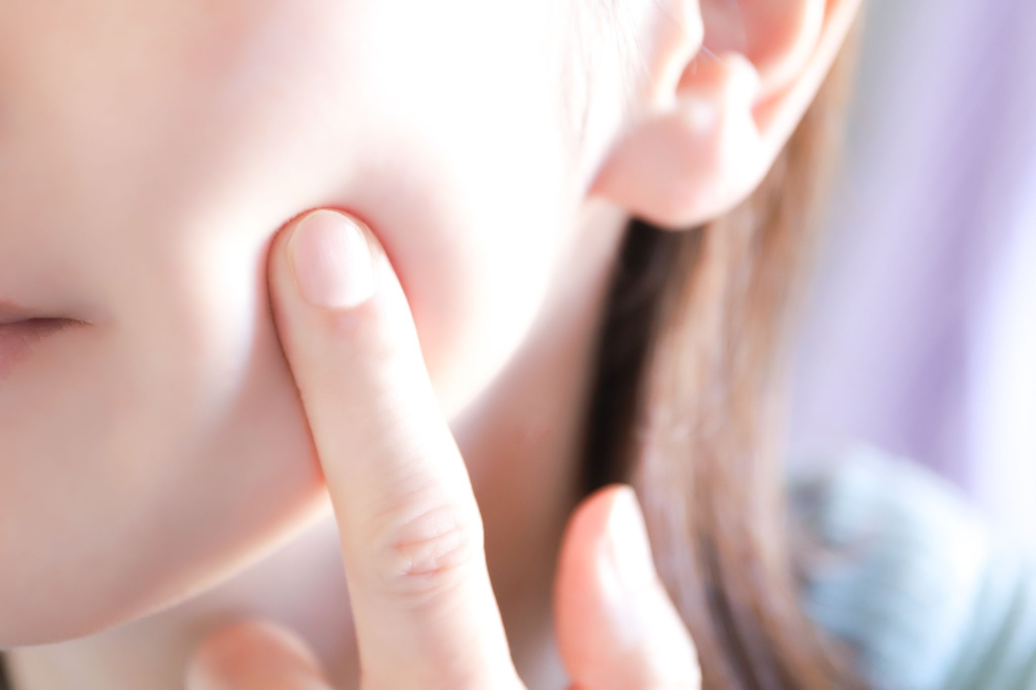 頬に指を当てている女性