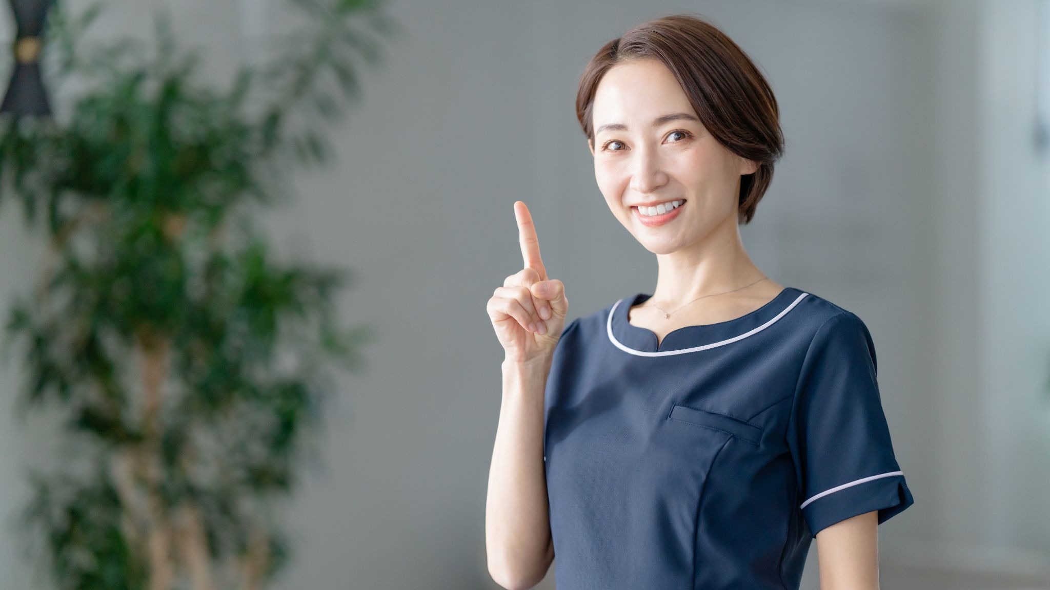 人差し指を立てた美容クリニックスタッフの女性